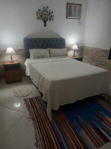 a bedroom with a large bed and two night stands with lamps at CASA EM PRAIA SECA in Araruama