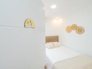een witte slaapkamer met een bed en hoeden aan de muur bij Cubo's Hostal William's Sunny 5 with Breakfast in Torre de Benagalbón