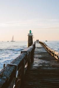 a wooden pier with a light house on the ocean at Res au calme et arboree in Dax
