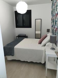 a bedroom with a large white bed and a mirror at LHOME CÁDIZ in Cádiz