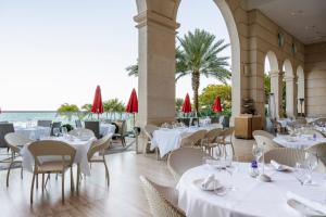 un restaurante con mesas y sillas blancas y el océano en Acqualina Resort and Residences, en Miami Beach