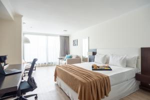 Zimmer mit einem großen Bett, einem Schreibtisch und einem Computer in der Unterkunft After Hotel Montevideo in Montevideo