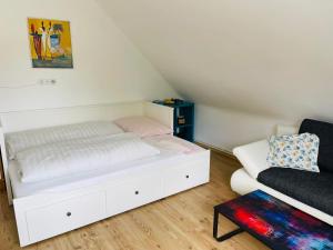 a bedroom with a white bed and a couch at APARTMENT Schlossbergblick in Griffen