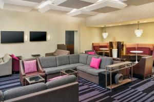 a living room with couches and chairs and a tv at Courtyard by Marriott New York JFK Airport in Queens