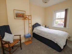 a bedroom with a bed and a chair and a window at Penny Cottage in Ludlow