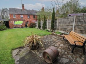 a garden with a bench and a fence and a house at Penny Cottage in Ludlow
