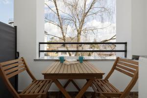a wooden table and two chairs on a balcony at Apartament ANTEK Dziwnówek nad morzem in Dziwnówek