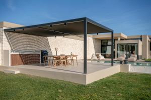 a covered patio with a table and a dining room at Pnoe Villas - Seafront Experience in Tavronitis