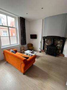 a living room with an orange couch and a fireplace at Appartementen het Centrum in Domburg