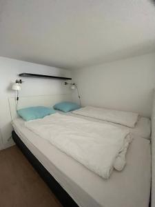 Bett mit weißer Bettwäsche und blauen Kissen in einem Zimmer in der Unterkunft Appartementen het Centrum in Domburg