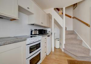 uma cozinha com armários brancos e uma escadaria em The Den em Lynmouth