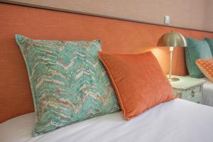 a bed with an orange and green pillow and a lamp at Dom José Alojamentos by Guestify in Guimarães