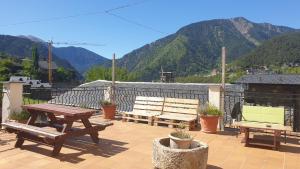 a patio with benches and a table with mountains in the background at Residencia Aldosa in LʼAldosa
