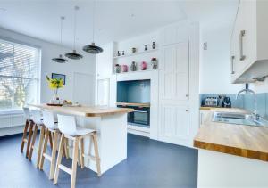 uma cozinha com armários brancos e um balcão com bancos em The Edwardian House em Ilfracombe