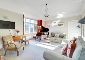 uma sala de estar com um sofá e um piano em The Edwardian House em Ilfracombe