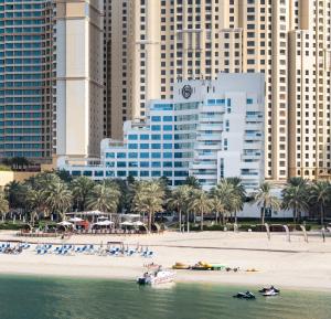 منتجع شيراتون جميرا بيتش  في دبي: اطلاله على شاطئ فيه مباني والنخيل