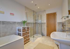 a bathroom with a tub and a sink and a shower at The Farthings in Ilfracombe