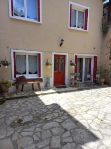 a house with red doors and a stone patio at Au Soleil Couchant in Sarlat-la-Canéda
