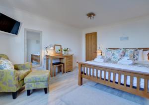 a bedroom with a bed and a chair and a tv at Farthings Nest in Ilfracombe