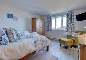 a bedroom with a bed and a chair and a window at Farthings Nest in Ilfracombe