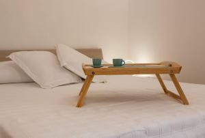 una mesa de madera en una cama con dos tazas. en Alloggio Turistico Flavia, en Anzio