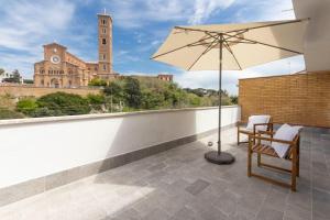 un patio con sombrilla, mesa y sillas en Alloggio Turistico Flavia, en Anzio