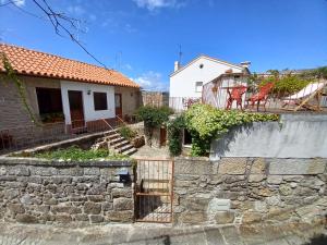 uma casa com uma parede de pedra ao lado de um edifício em Refúgio do Anjo - Alojamento Local em Lanhelas