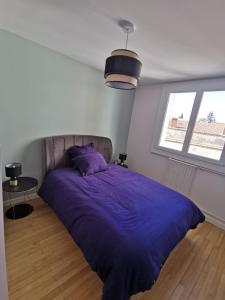 ein Schlafzimmer mit einem großen lila Bett und einem Fenster in der Unterkunft Magnifique Appartement Esprit Art Déco in Romans-sur-Isère