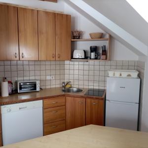 a kitchen with wooden cabinets and a white refrigerator at JULIJA 3 SUNNY APPARTMENT in Kranjska Gora