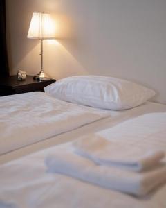 1 cama con sábanas blancas, almohada y lámpara en Fisherman Guesthouse Flateyri, en Flateyri