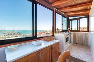 Una cocina con grandes ventanales y vista al mar. en Appartamento Il Belvedere - MyHo Casa, en Vieste