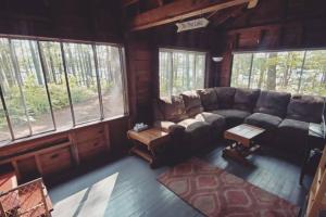 a living room with a couch and a table and windows at Grant Island Waterfront Cottage Brantingham Lk - Dogs Love - Worlds Raddest Island in Glenfield