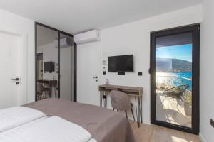 a bedroom with a bed and a desk and a balcony at Seafront villa with roofpool, perfect getaway in Vinišće +75 photos