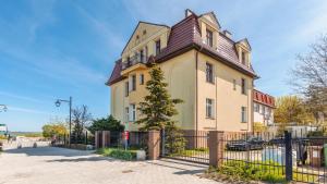a large yellow house with a brown roof at Apartamenty Sun & Snow Traugutta Plaża in Sopot