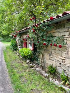 a stone building with red roses growing on it at Chambre en bordure d'Aveyron in Saint-Antonin