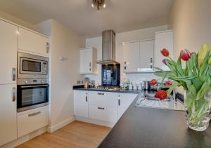 a kitchen with white cabinets and a vase of red tulips at Harbour Heights Ilfracombe in Ilfracombe