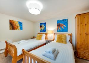 two beds in a bedroom with blue paintings on the wall at Harbour Heights Ilfracombe in Ilfracombe