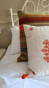 uma cama com lençóis brancos e almofadas com fios vermelhos em The Cricketers Inn em Petersfield