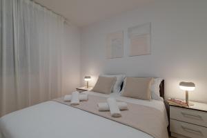 een witte slaapkamer met een groot bed met 2 lampen bij Apartman Marino in Trogir