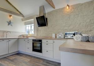 a kitchen with white cabinets and a tv on the wall at Hideaway in Appledore