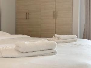 drei weiße Handtücher auf dem Bett in der Unterkunft Iakovaton Modern 62sqm in Athens in Athen