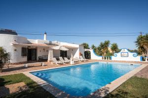a villa with a swimming pool in front of a house at Vivenda Solar dos Pescadores in Armação de Pêra