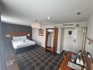 ein Hotelzimmer mit einem Bett und einem Tisch in der Unterkunft The Queen Hotel Wetherspoon in Aldershot