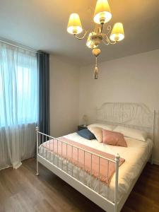 a bedroom with a white bed with a chandelier at Maison Bon Ton in Villafranca dʼAsti