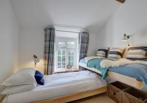 two beds in a room with a window at July Cottage in West Down