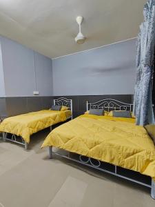 a bedroom with two beds with yellow sheets and a ceiling at TBE Room2stay at Jalan BR3 in Melaka