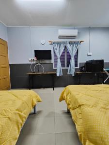 two beds in a room with yellow sheets at TBE Room2stay at Jalan BR3 in Malacca