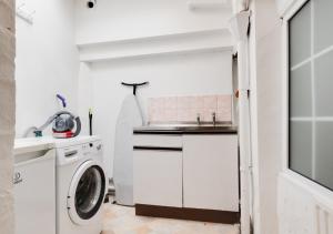 a white kitchen with a washing machine and a sink at Kimblewick in Braunton