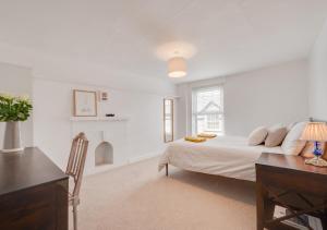 a white bedroom with a bed and a desk at Kimblewick in Braunton