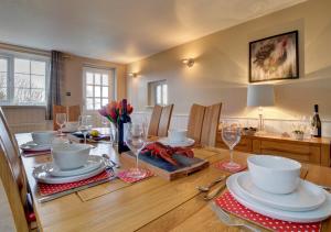 a dining room table with plates and wine glasses at Keepers Cottage Lynton in Barbrook